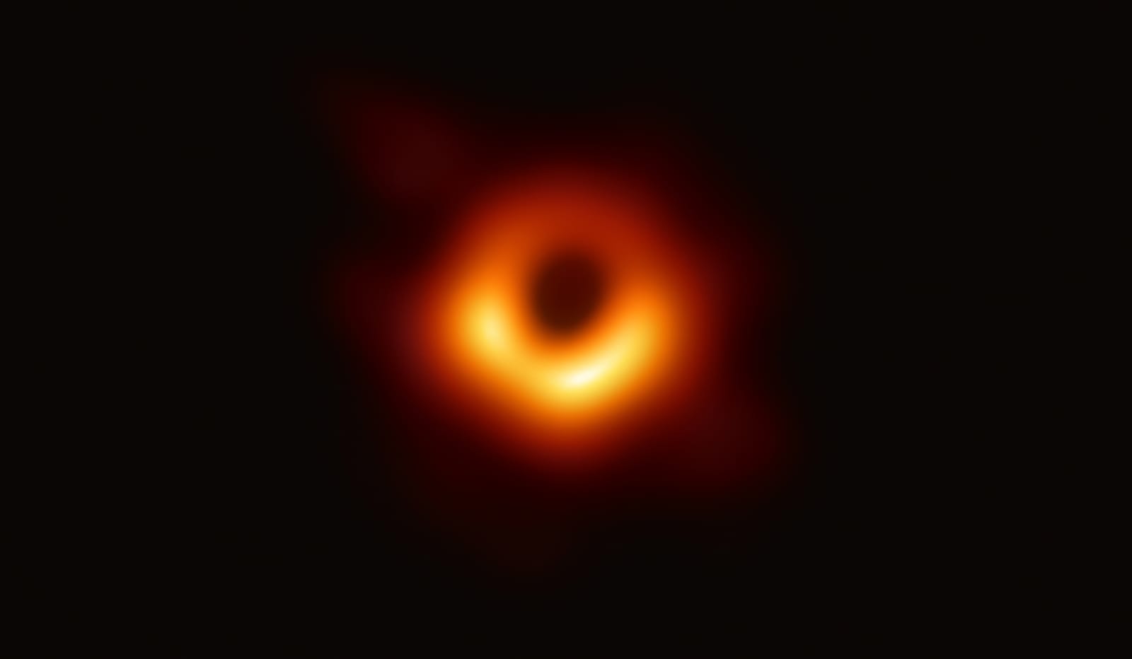The first image of a supermassive black hole at the center of galaxy M87, 55 million light-years from Earth. The orange ring is hot gas swirling around a dark central shadow. Credit: EHT Collaboration (CC BY 4.0).