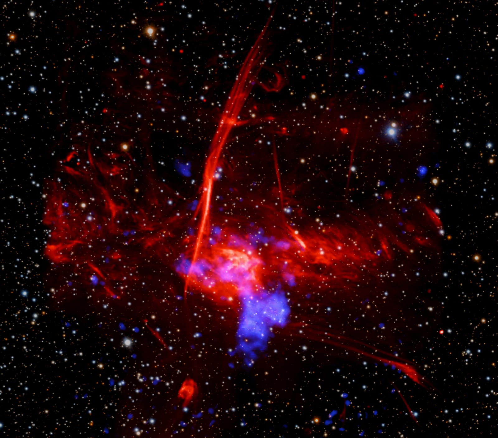 Composite image of Sagittarius C showing X-ray emission from Chandra and XMM-Newton (blue) embedded within radio emission from MeerKAT (red) against an optical starfield from Pan-STARRS. The location of the suspected supernova remnant is circled. Credit: X-ray: NASA/CXC/UCLA/Z. Zhu et al.; ESA/XMM-Newton; Optical: PanSTARRS; Radio: MeerKAT; Image Processing: NASA/CXC/SAO/L. Frattare and P. Edmonds.